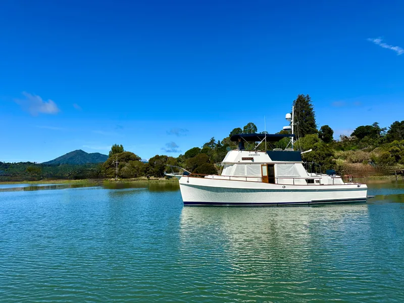 Slide: The Image of 1989 Grand Banks 42 Classic yacht on serene water with lush green backdrop. - 2