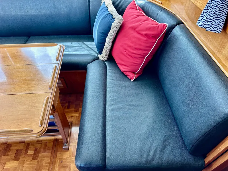 Slide: The Image of Grand Banks 42 Classic 1989 interior with blue seating, red cushion, and wooden table. - 26