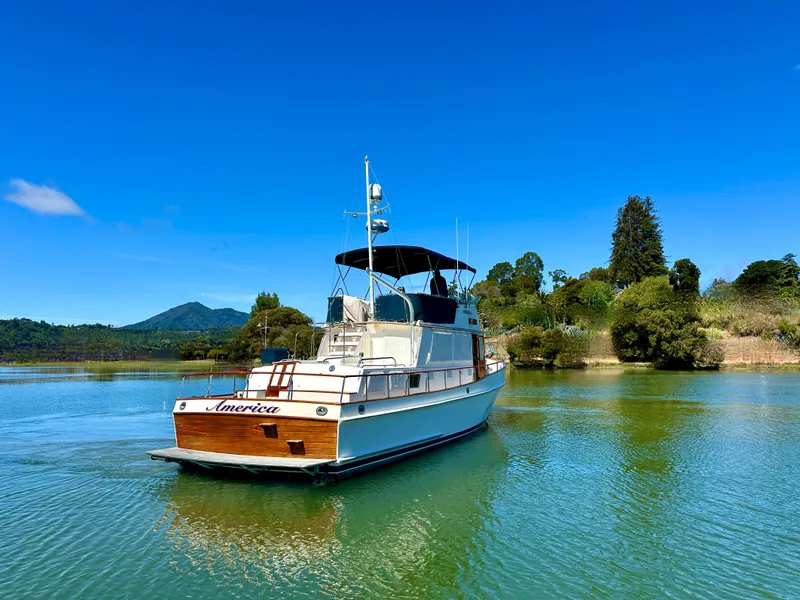 Slide: The Image of 1989 Grand Banks 42 Classic yacht on serene water with lush greenery backdrop. - 6