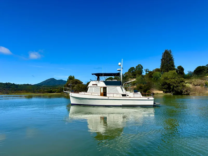 Slide: The Image of 1989 Grand Banks 42 Classic yacht on serene water with lush green landscape. - 8