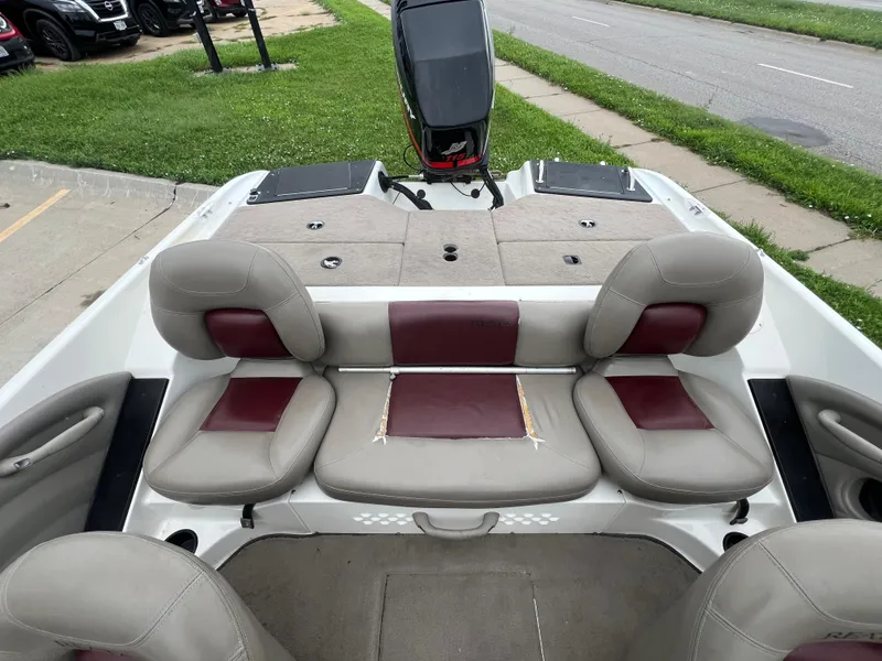 Slide: The Image of 2004 Ranger 180 Reata boat interior with beige and maroon seating, parked near a road. - 10
