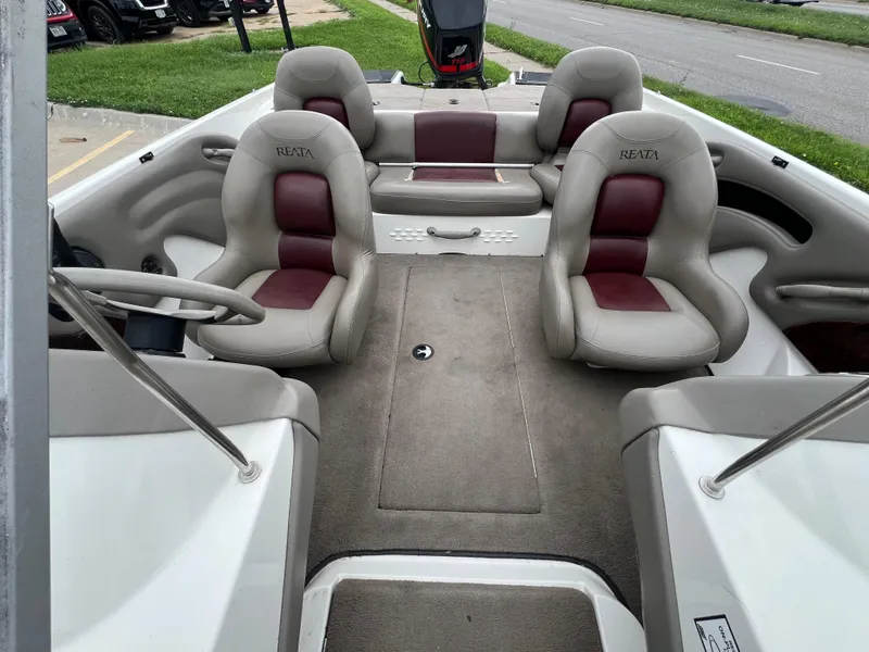 Slide: The Image of 2004 Ranger 180 Reata boat interior with beige and maroon seating, steering wheel, and carpeted floor. - 7