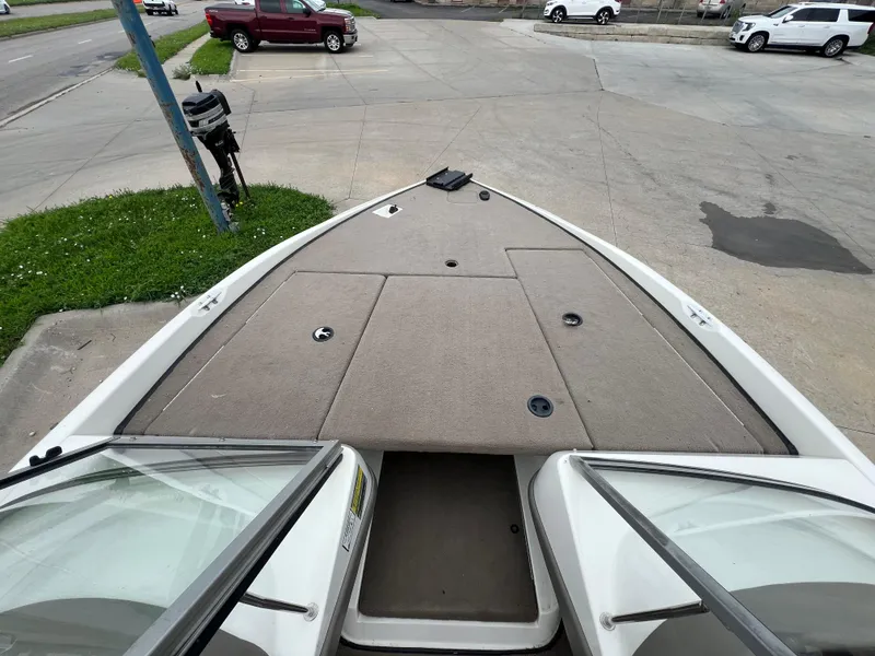 Slide: The Image of 2004 Ranger 180 Reata boat interior with open deck, parked near vehicles. - 8