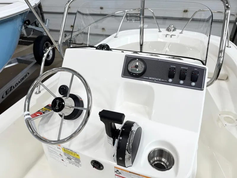 Slide: The Image of 2025 Boston Whaler 150 Montauk boat dashboard with steering wheel and controls. - 7