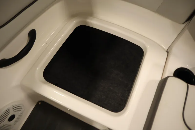 Slide: The Image of 2021 Yamaha Boats 190 AR interior storage compartment with black mat and white trim. - 35