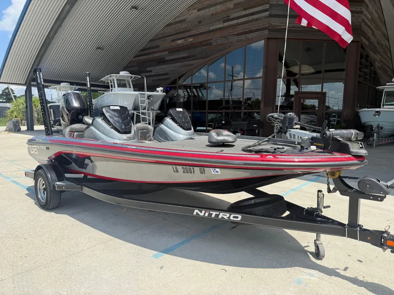 Slide: The Image of 2016 Nitro Z18 boat on trailer, parked outside a modern building with an American flag. - 2
