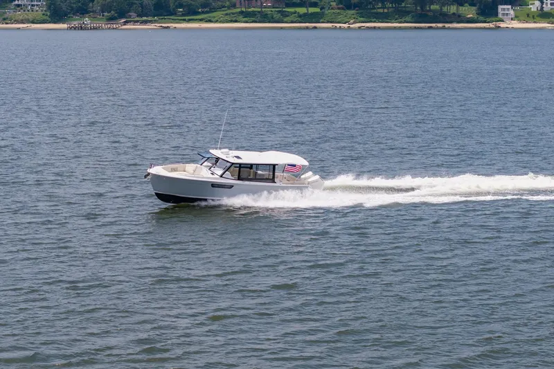 Slide: The Image of 2025 MJM 3 boat cruising on a calm lake with shoreline in the background. - 14