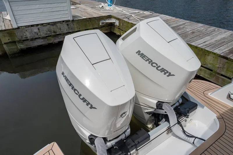 Slide: The Image of Twin Mercury outboard engines on a 2025 MJM 3 boat docked by the water. - 17