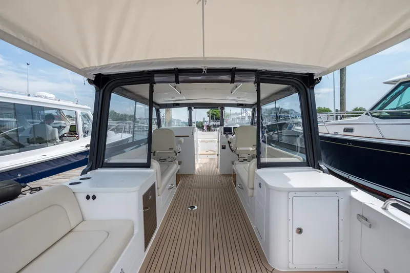 Slide: The Image of 2025 MJM 3 boat interior with seating, helm, and canopy in marina setting. - 20