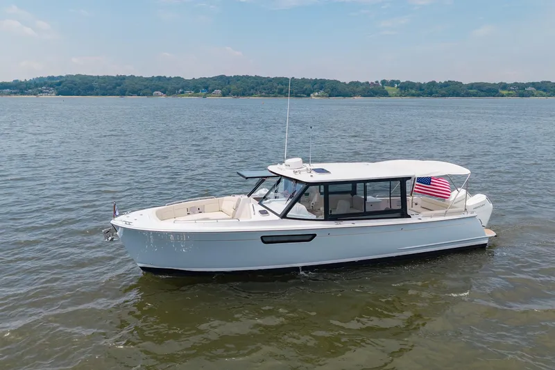Slide: The Image of 2025 MJM 3 boat on calm water with American flag, clear sky background. - 3