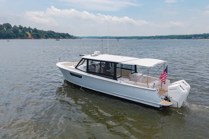 Slide: The Image of 2025 MJM 3 boat cruising on a calm lake with scenic shoreline. - 5