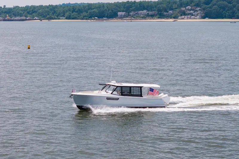 Slide: The Image of 2025 MJM 3 boat cruising on a calm lake with scenic shoreline. - 6