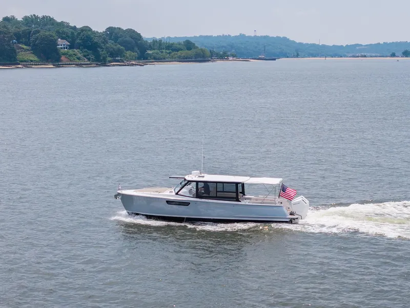 Slide: The Image of 2025 MJM 3 boat cruising on a scenic lake with lush green shoreline. - 7