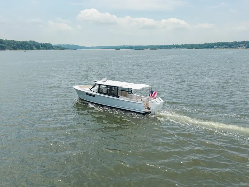 Slide: The Image of 2025 MJM 3 boat cruising on a calm lake with an American flag. - 9