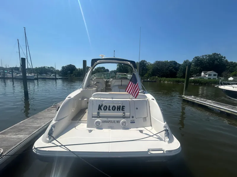 Slide: The Image of 2008 Sea Ray 330 Sundancer docked, displaying American flag, sunny day, calm waters. - 2