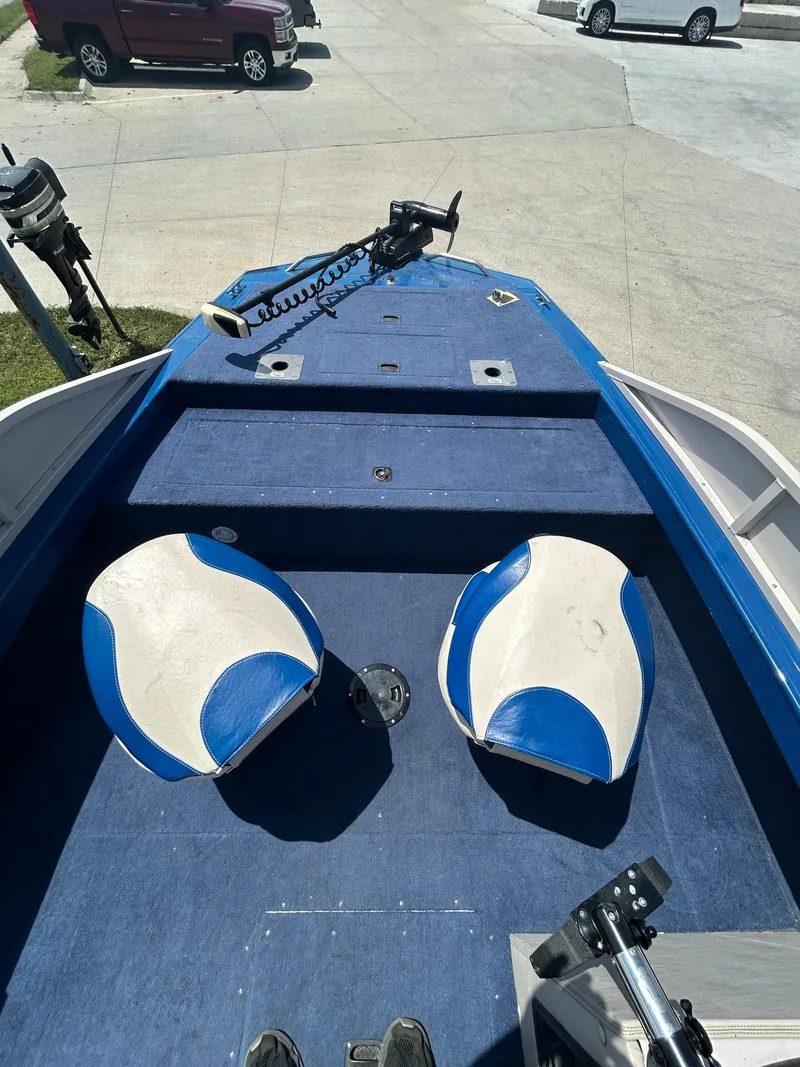 Slide: The Image of 1999 Crestliner Rampage 2000 boat interior with blue and white seats, parked on concrete. - 5