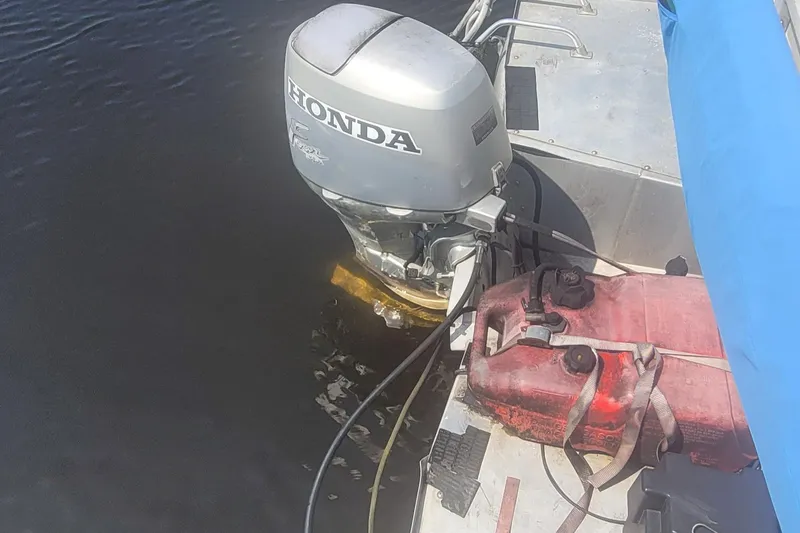 Slide: The Image of Outboard motor on a 1997 Beachcomber Beach boat with fuel tank, docked on water. - 3