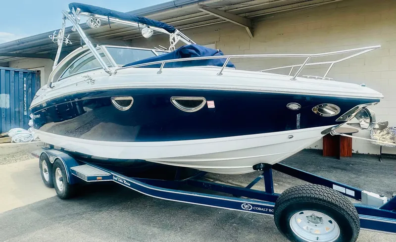 Slide: The Image of 2012 Cobalt 243 boat on trailer, blue and white, parked outdoors. - 1