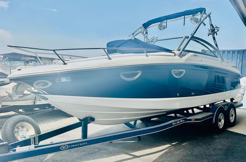 Slide: The Image of 2012 Cobalt 243 boat on trailer, blue and white design, parked outdoors. - 6