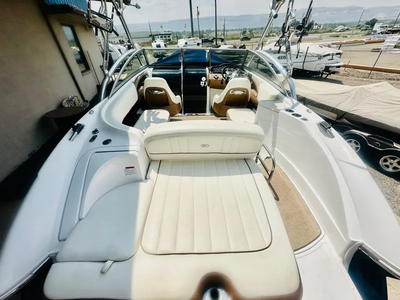 Slide: The Image of 2012 Cobalt 243 boat interior with white seating and dashboard, parked outdoors. - 8