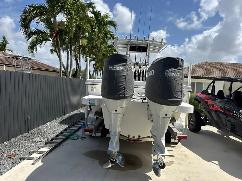 Slide: The Image of 2015 Ocean Master 296 boat with dual Suzuki outboard motors, parked near palm trees. - 2