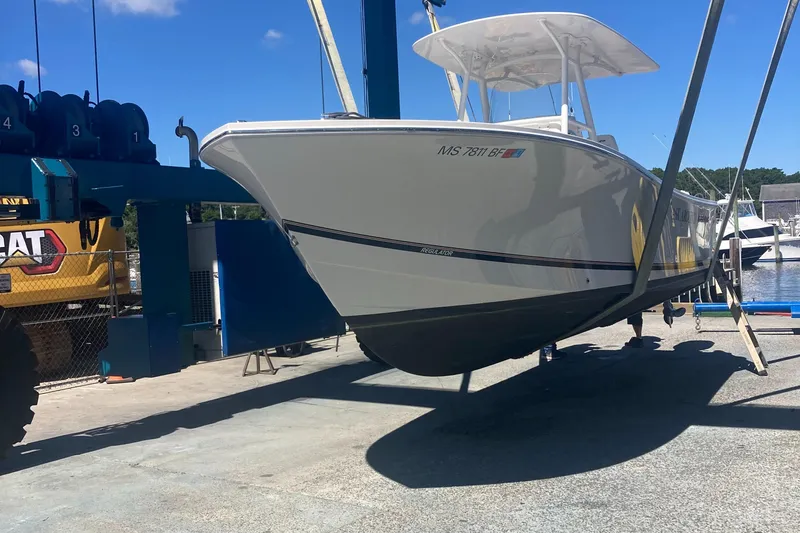 Slide: The Image of 2015 Regulator 25FS Center Console boat being lifted at a marina. - 2