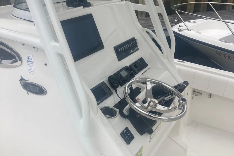 Slide: The Image of 2015 Regulator 25FS Center Console boat dashboard with steering wheel and electronic controls. - 34