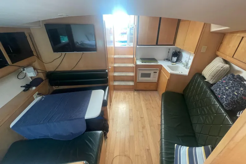 Slide: The Image of Interior of 1998 Hatteras 39 Sport Express with seating, table, TV, and kitchenette. - 12