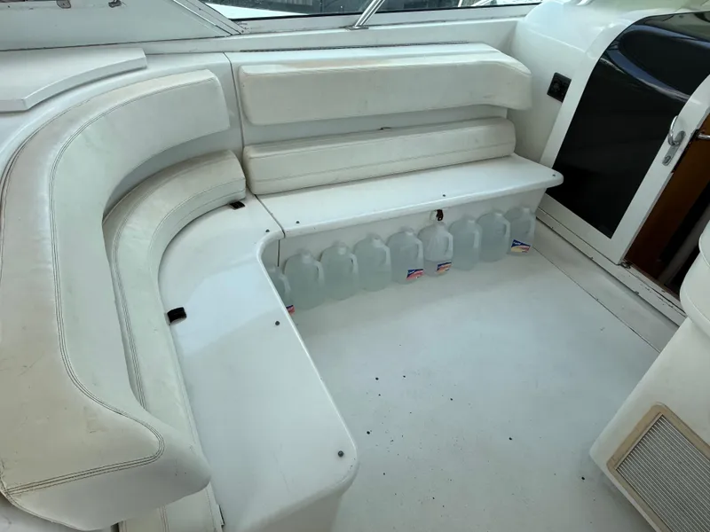 Slide: The Image of White seating area on 1998 Hatteras 39 Sport Express boat with water jugs stored underneath. - 8