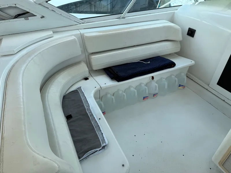 Slide: The Image of White seating area on 1998 Hatteras 39 Sport Express boat with water jugs stored underneath. - 9