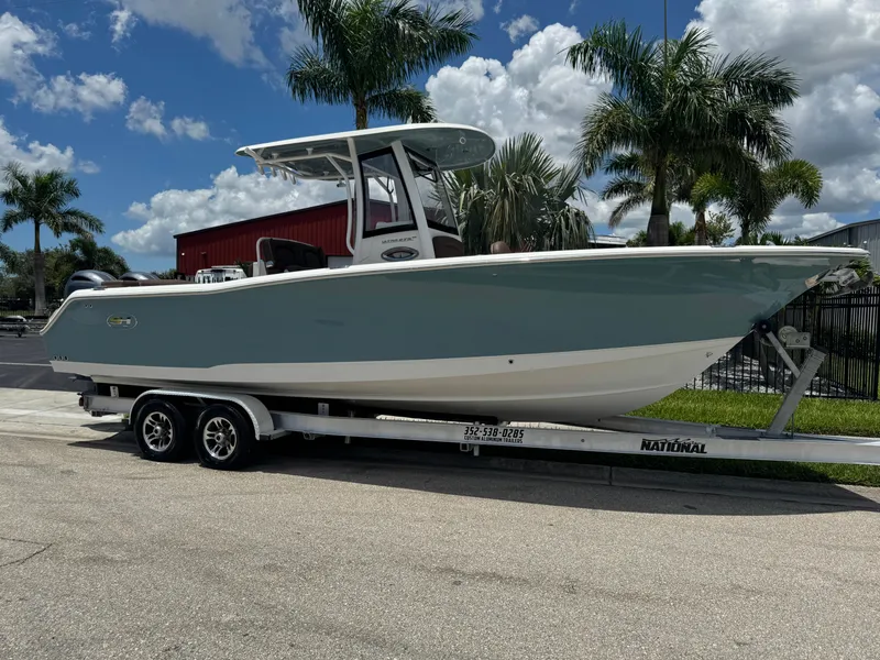 Slide: The Image of 2019 Sea Hunt Ultra 275 SE boat on trailer, parked near palm trees under a blue sky. - 3