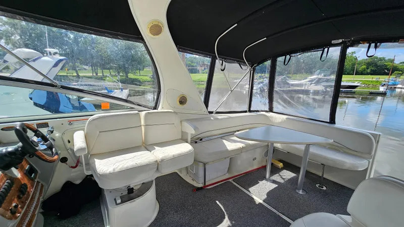 Slide: The Image of 2009 Bayliner 340 SB boat interior with seating and table, docked by a serene lake. - 10