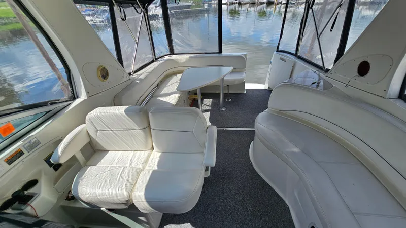 Slide: The Image of 2009 Bayliner 340 SB boat interior with white seating and table, overlooking water. - 5