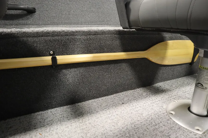 Slide: The Image of 2023 Tracker V16 Pro Guide WT boat interior with wooden paddle secured on carpeted floor. - 30