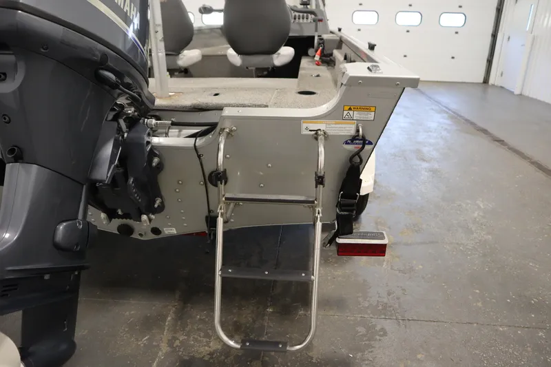 Slide: The Image of 2013 Alumacraft 165 Classic SC boat with Yamaha motor and rear ladder in garage. - 47