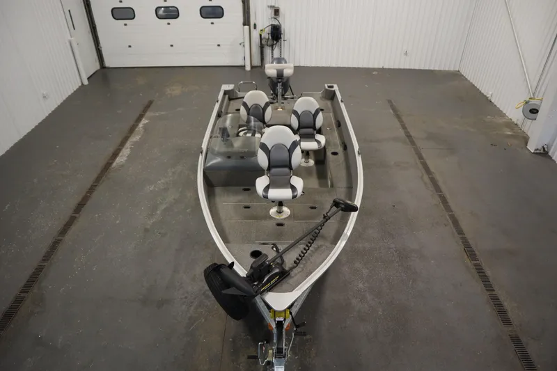 Slide: The Image of 2013 Alumacraft 165 Classic SC fishing boat in a garage, featuring multiple seats and trolling motor. - 9