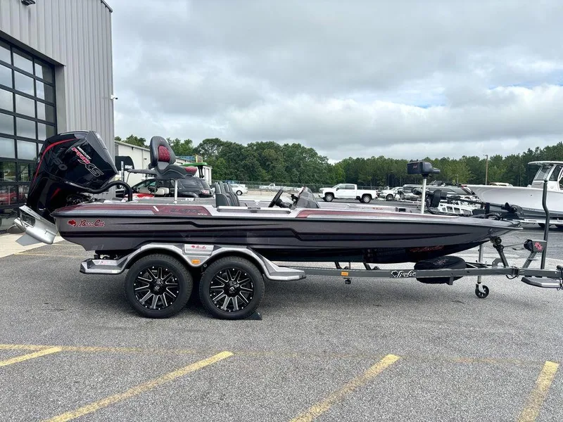The Image of 2026 Bass Cat Lynx STS boat on trailer, parked outdoors near a building. - 0