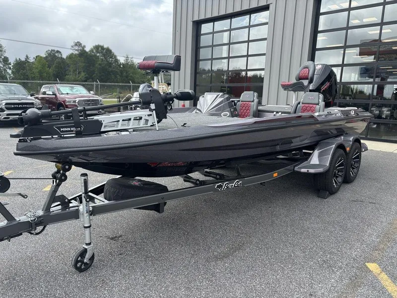Slide: The Image of 2026 Bass Cat Lynx STS fishing boat on trailer, parked outside a garage. - 12