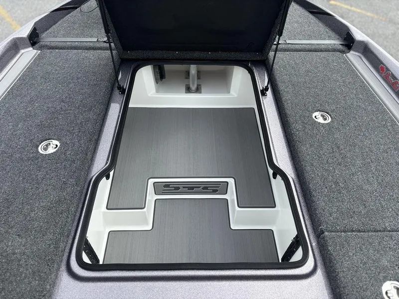 Slide: The Image of 2026 Bass Cat Lynx STS boat storage compartment with open lid, featuring sleek design and carpeted surfaces. - 18