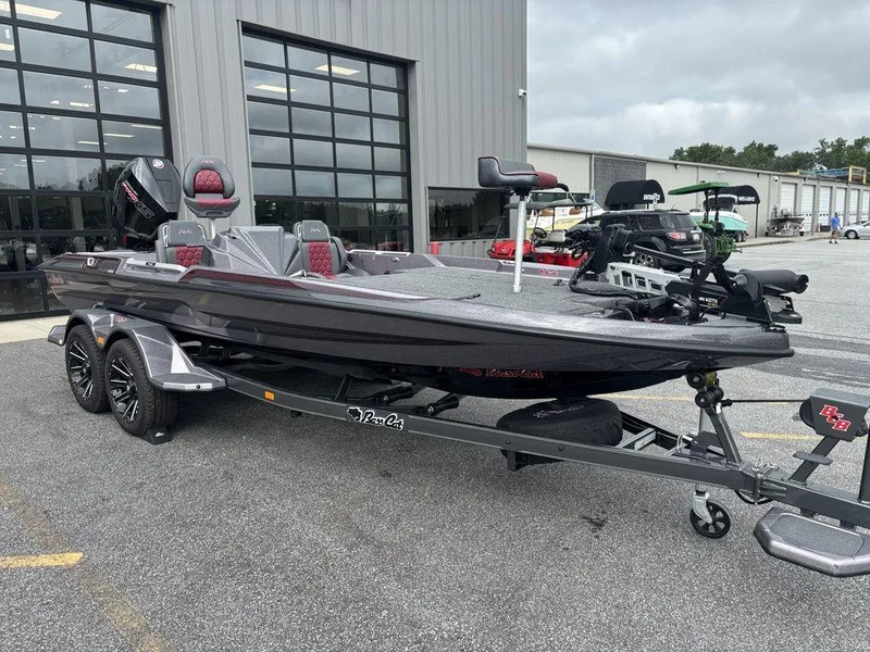 Slide: The Image of 2026 Bass Cat Lynx STS fishing boat on trailer, parked outside a garage. - 2