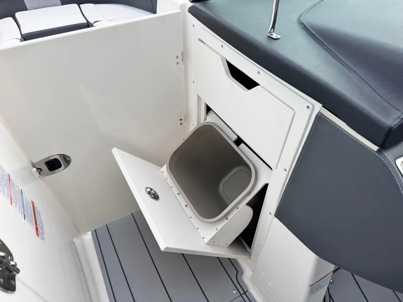 Slide: The Image of 2025 Chaparral 307 SSX boat interior with open storage compartment and trash bin. - 10