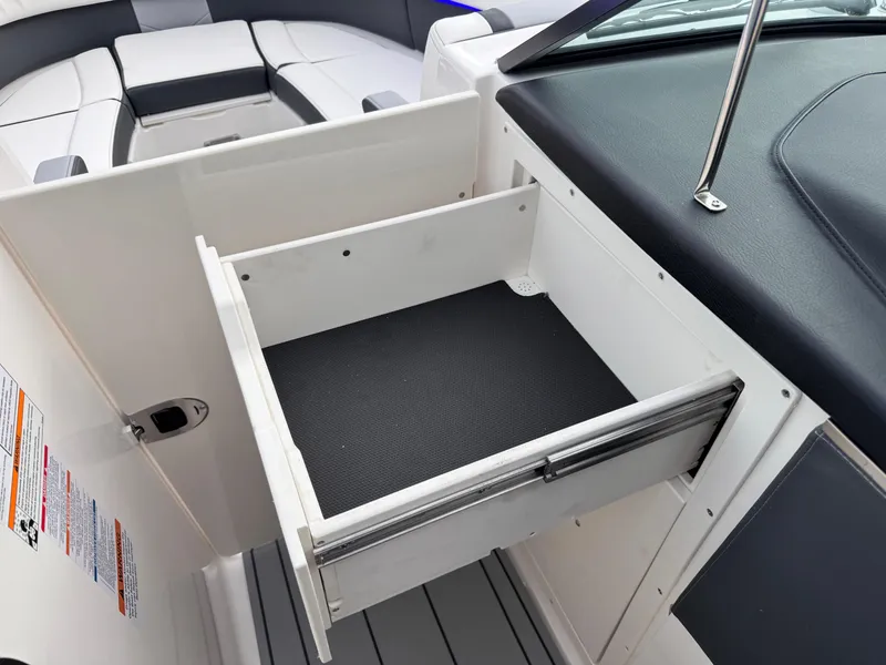 Slide: The Image of 2025 Chaparral 307 SSX boat interior with open storage drawer and seating area. - 11