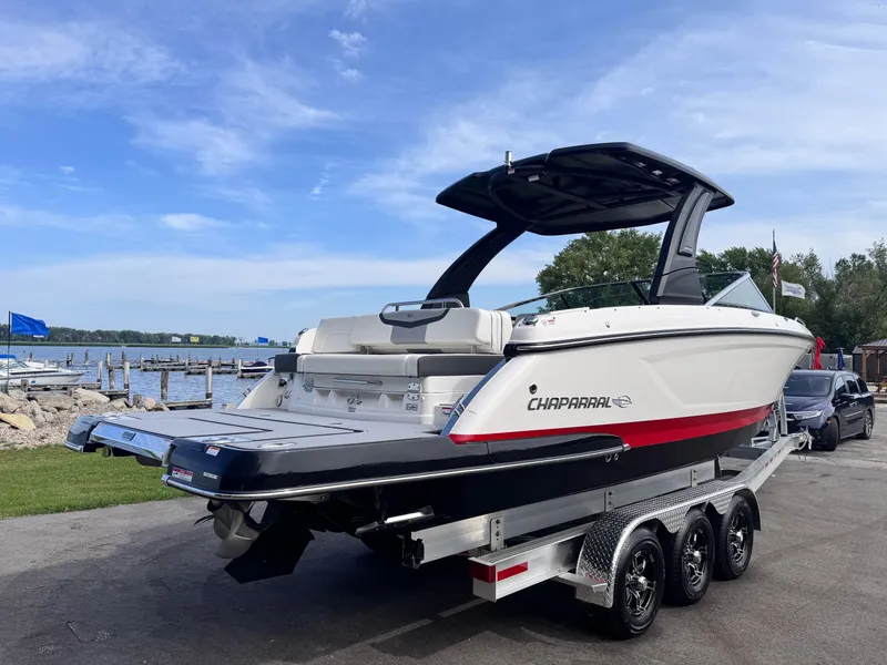 Slide: The Image of 2025 Chaparral 307 SSX boat on trailer by lakeside, under clear blue sky. - 4