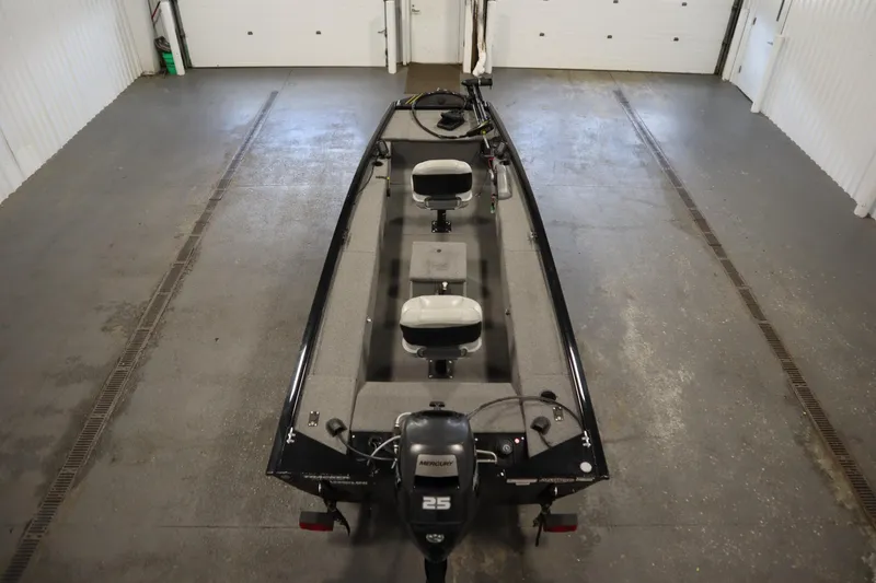 Slide: The Image of 2018 Tracker Panfish 16 boat in a garage, featuring two seats and a Mercury 25 outboard motor. - 10