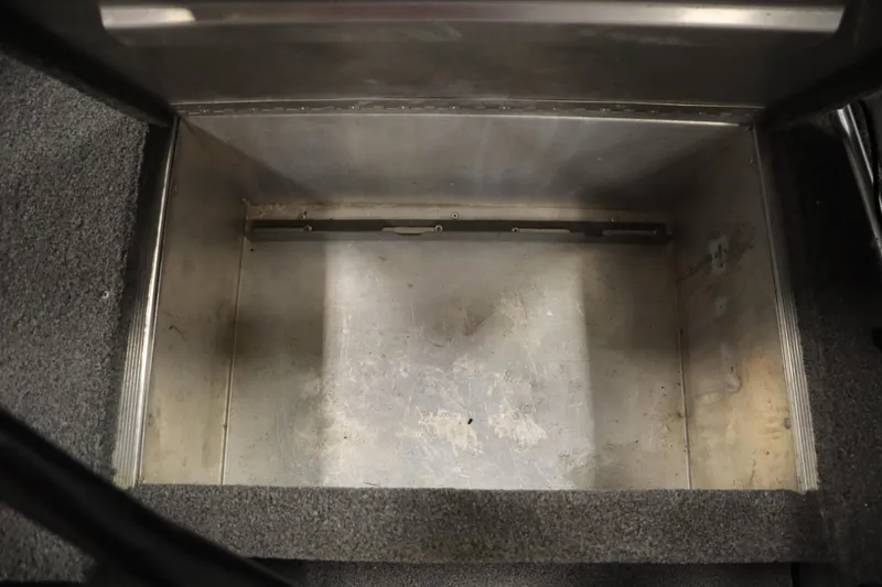 Slide: The Image of Empty storage compartment in 2018 Tracker Panfish 16 boat, featuring metal interior and carpeted edges. - 15