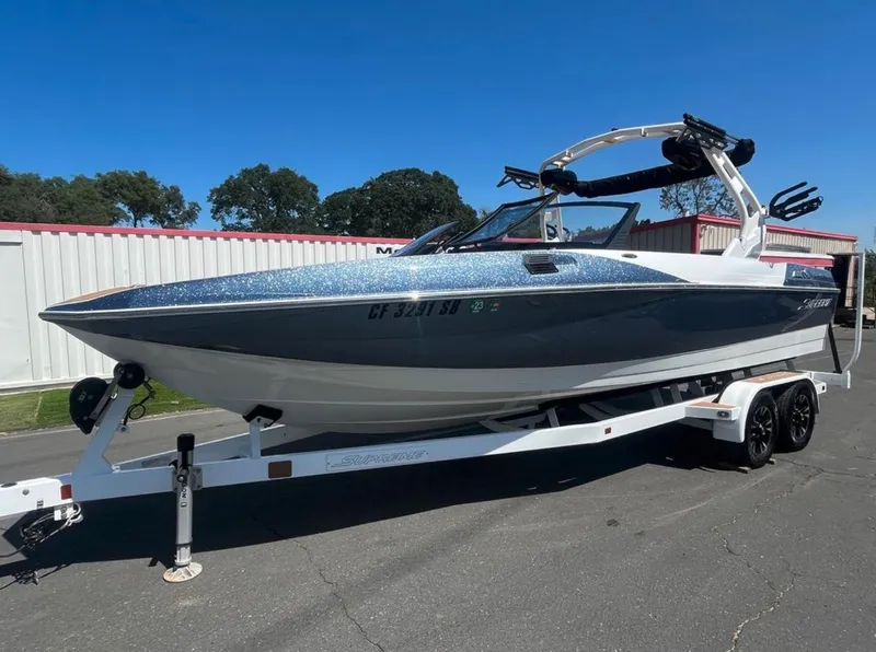 Slide: The Image of 2021 Supreme S 238 boat on trailer, parked outdoors under clear blue sky. - 22