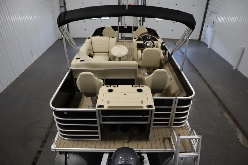 Slide: The Image of 2019 Sylvan 820 Mirage pontoon boat with beige seating and black canopy in a garage. - 11