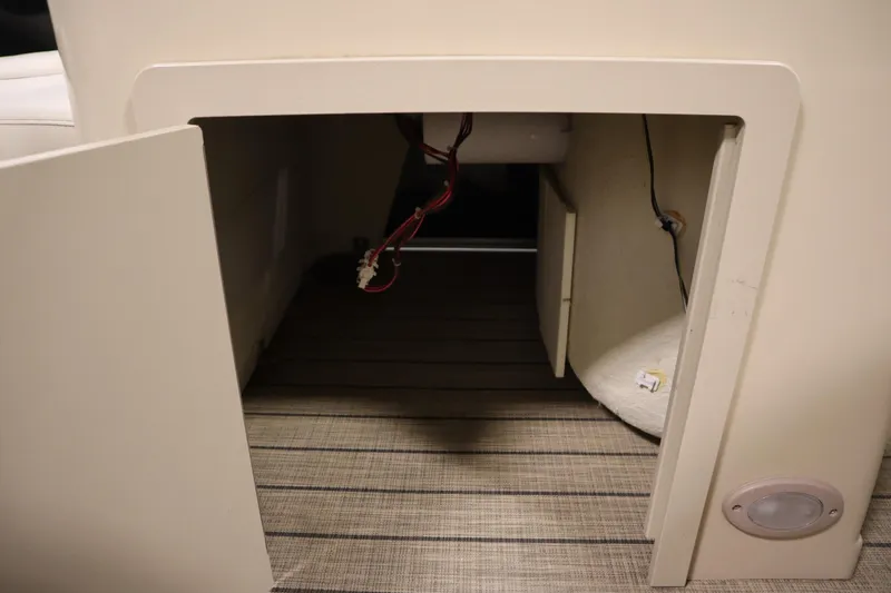 Slide: The Image of Open storage compartment in 2019 Sylvan 820 Mirage boat, showing interior wiring and carpeted floor. - 18