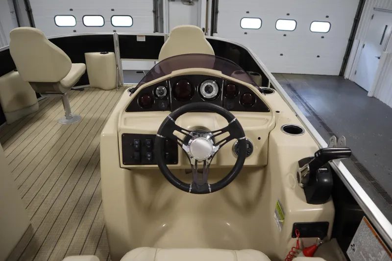 Slide: The Image of 2019 Sylvan 820 Mirage boat interior with steering wheel and seating in a garage. - 19
