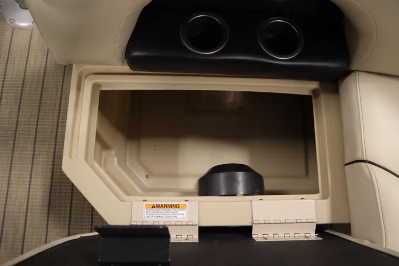 Slide: The Image of Storage compartment in 2019 Sylvan 820 Mirage boat with cup holders and warning label. - 32
